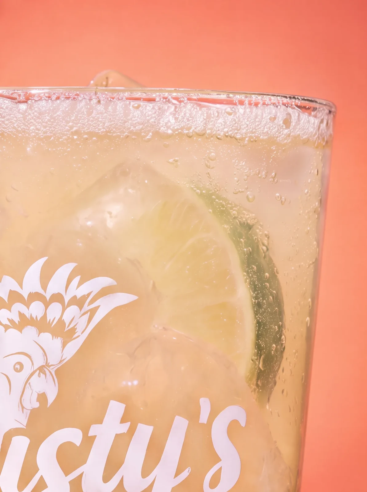 Close-up of a branded Dusty's pint glass with lime, ice and bubbles