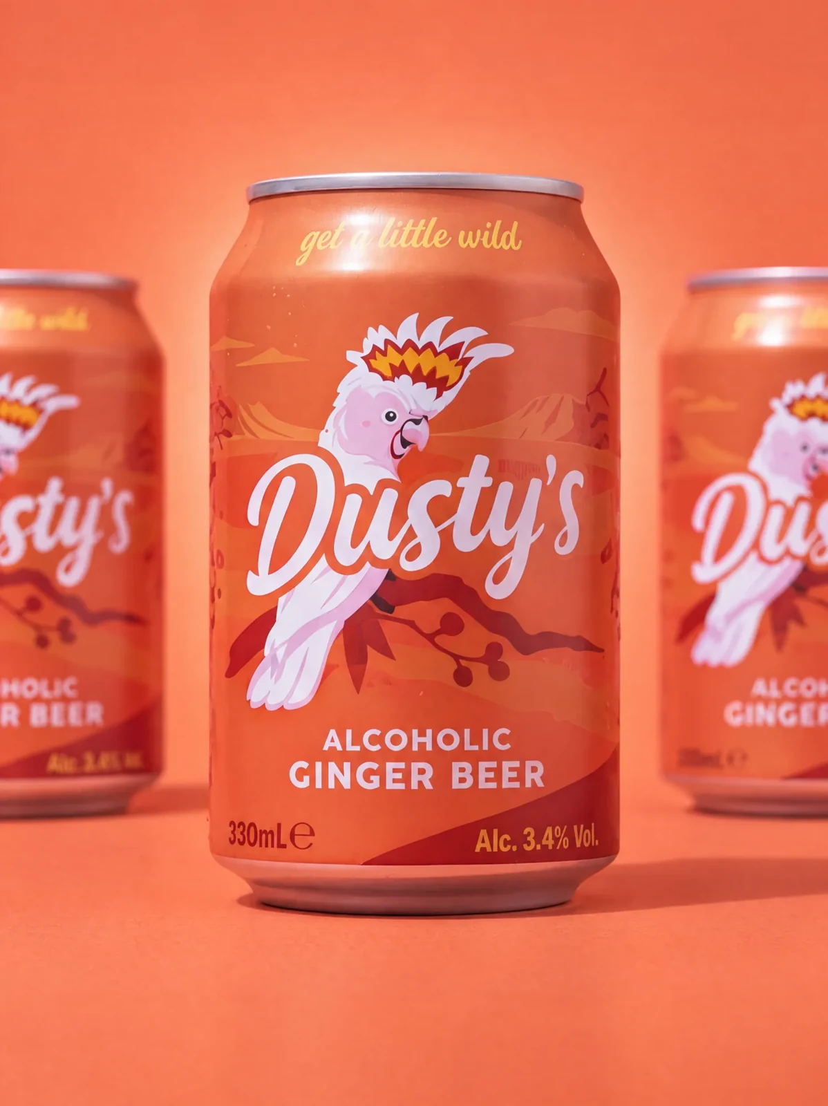 Three Dusty's Ginger Beer cans lined up against a coral background