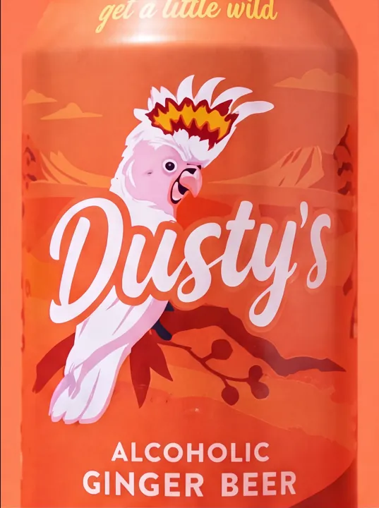 Close-up of the cockatoo illustration and Dusty's Ginger Beer logo on a coral can